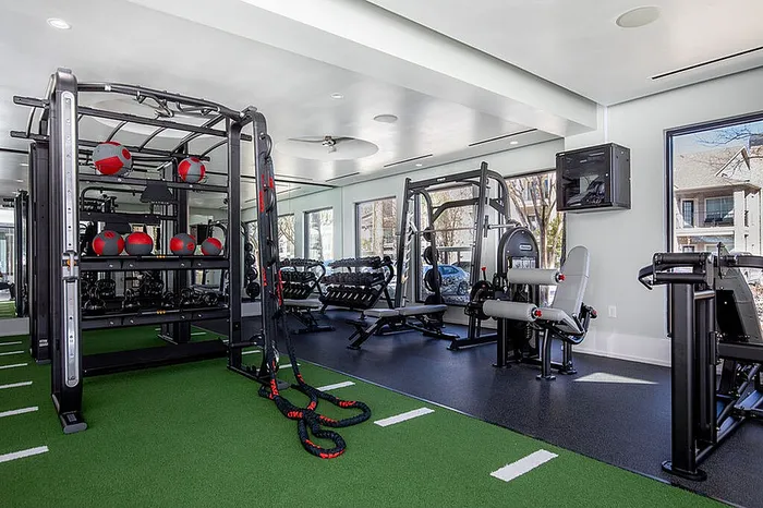 Modern fitness center with state-of-the-art equipment, featuring strength machines, medicine balls, and green turf flooring.