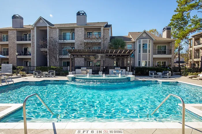 Luxurious apartment complex with a sparkling swimming pool, stylish outdoor seating, and elegant architectural design.