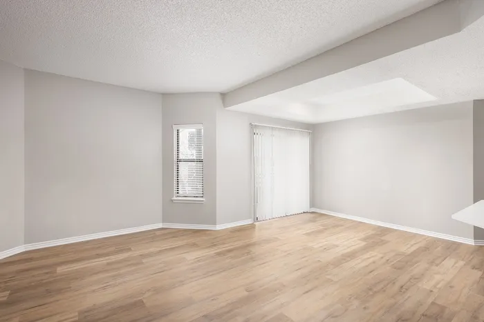 Bright and airy living space with elegant wood flooring and large windows featuring sleek blinds.