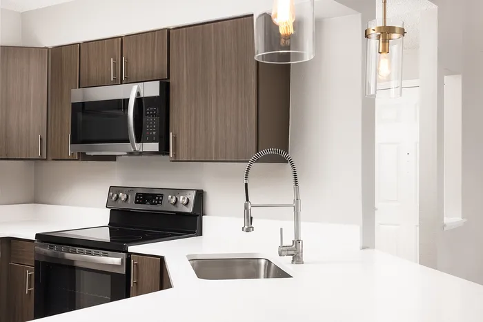 Modern kitchen with sleek stainless steel appliances, elegant cabinetry, and stylish pendant lighting.