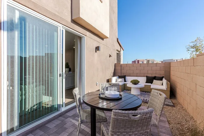 Charming outdoor patio with modern wicker furniture set, cozy seating area, and a sleek glass sliding door leading to the stylish interior.