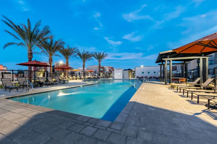 Luxurious poolside oasis with elegant lounge chairs, vibrant umbrellas, and serene palm trees at sunset.