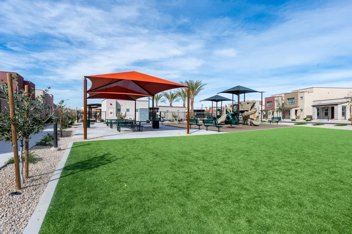 Modern apartment community with vibrant playground, shaded picnic area, and lush green landscaping.