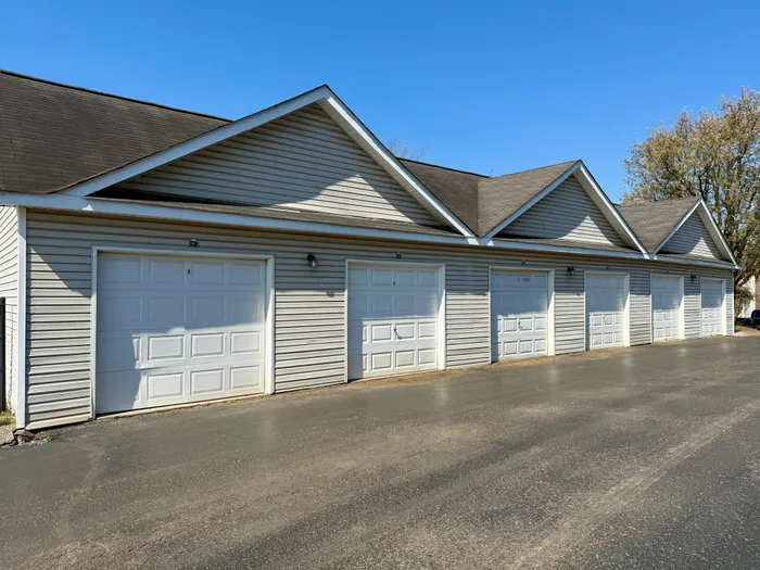 Modern multi-garage unit with clean white doors and pitched roofs in a suburban setting, perfect for secure vehicle storage.