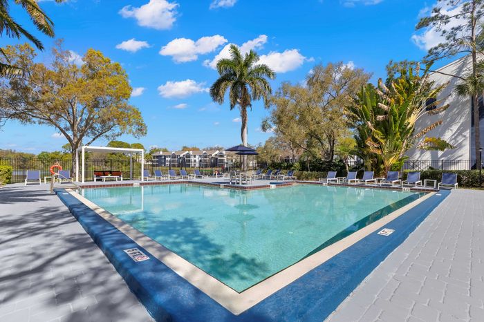 Inviting outdoor pool area with sun loungers under a vibrant blue sky, perfect for relaxation and leisure.