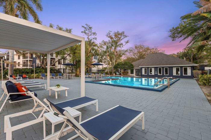 Inviting outdoor pool area with modern lounge chairs and a shaded seating zone, set against a serene evening sky.