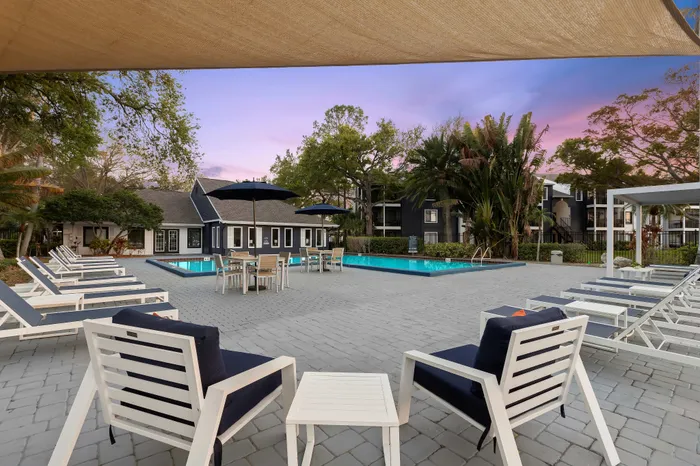 Relaxing poolside oasis with stylish lounge chairs, lush greenery, and vibrant sunset views.