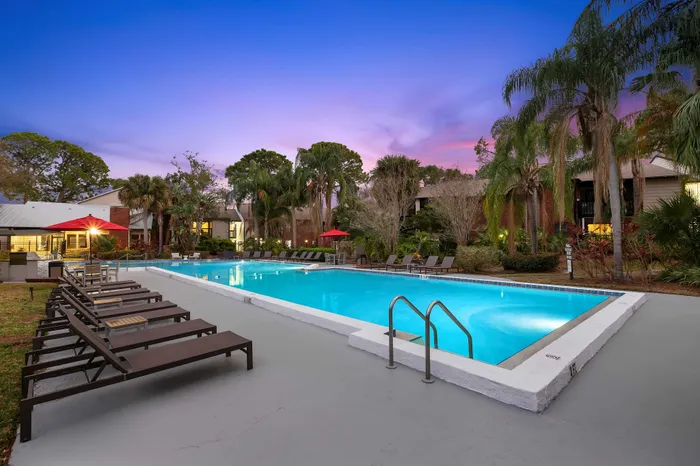 Inviting poolside oasis at sunset with lounge chairs and lush palm trees, perfect for relaxation and leisure.