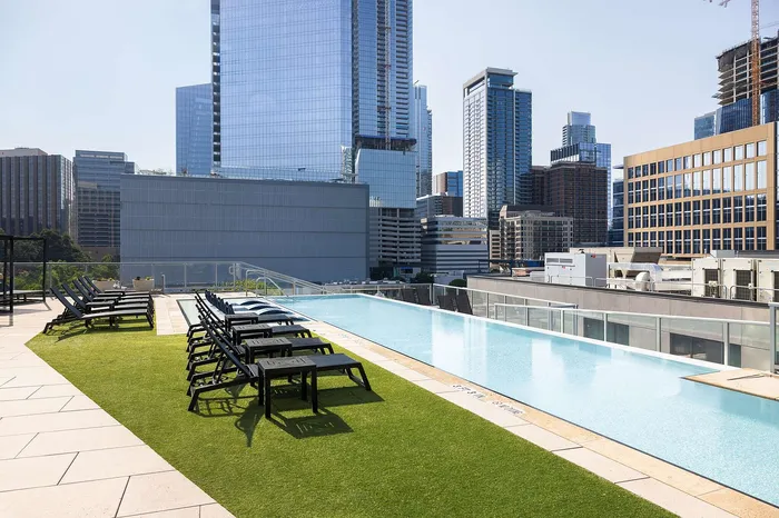 Sleek rooftop pool with stylish lounge chairs offering a breathtaking urban skyline view.