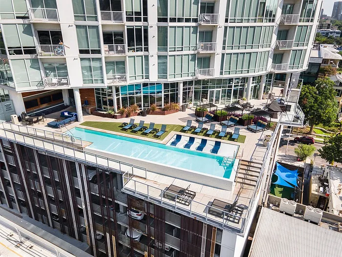 Luxurious apartment complex with a stunning rooftop pool, modern relaxation areas, and expansive city views.