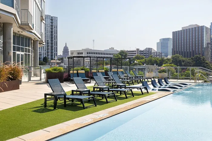 Luxurious rooftop pool area with stylish lounge chairs, offering stunning city skyline views.