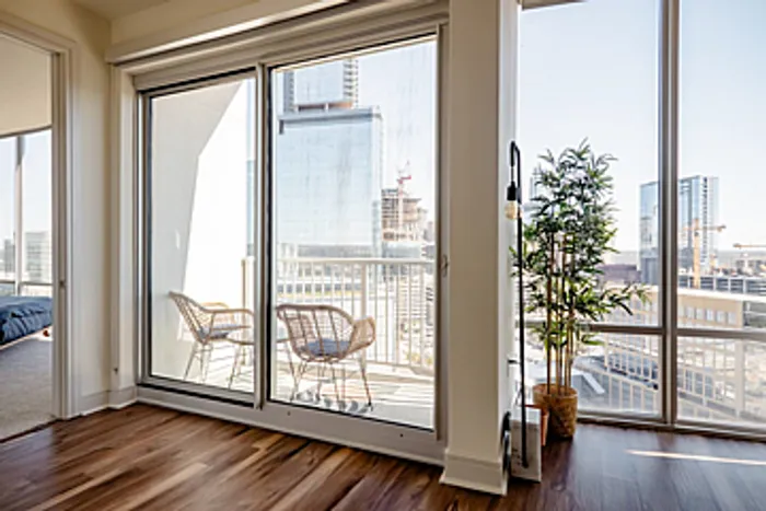 Bright urban apartment with stunning city view, featuring floor-to-ceiling windows and a cozy balcony seating area.
