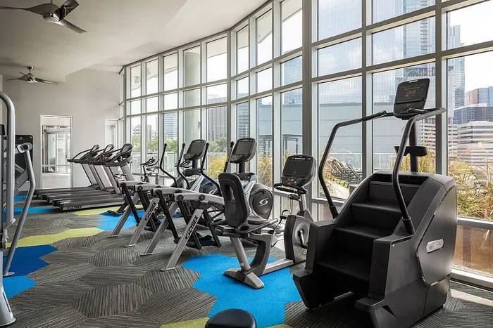 Bright and modern gym with state-of-the-art exercise equipment and large windows offering city views.