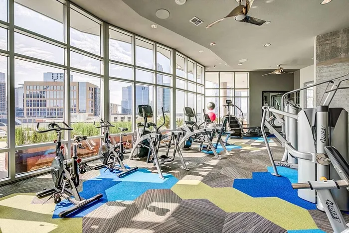 Contemporary fitness center with panoramic city views, featuring state-of-the-art exercise machines and vibrant decor.