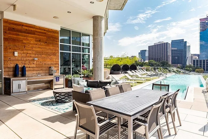 Luxurious rooftop terrace with modern dining area, stylish wooden accents, and sparkling pool with stunning cityscape views.