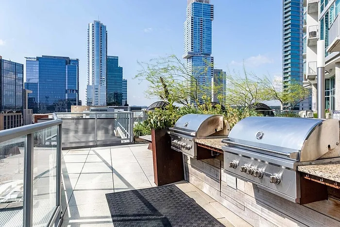 Stylish urban rooftop deck with modern stainless steel grills and stunning city skyline views.