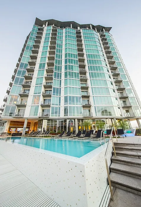 Impressive modern high-rise apartment building with expansive glass windows and a luxurious rooftop pool, offering unparalleled urban living experience.