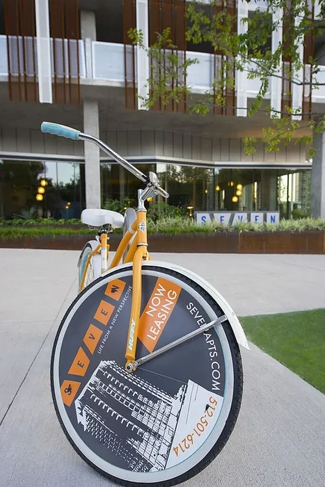 Modern apartment complex with eye-catching leasing advertisement on bicycle wheel; urban living at its finest.