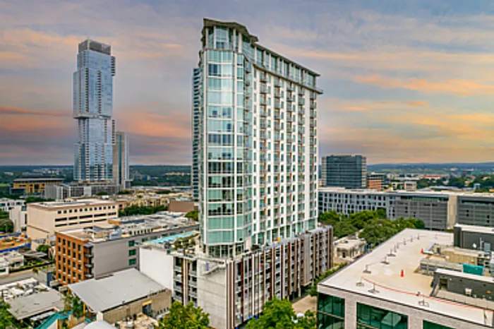 Modern high-rise building with sleek architecture set against a vibrant cityscape during a stunning sunset.