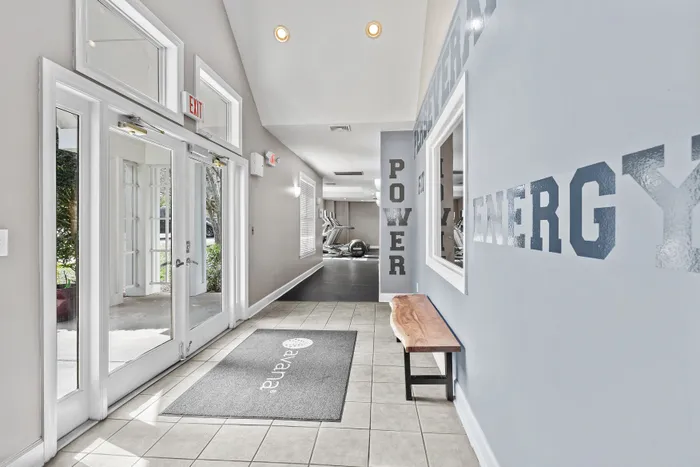 Bright and modern gym entrance with motivational wall art and sleek exercise equipment visible in the background.