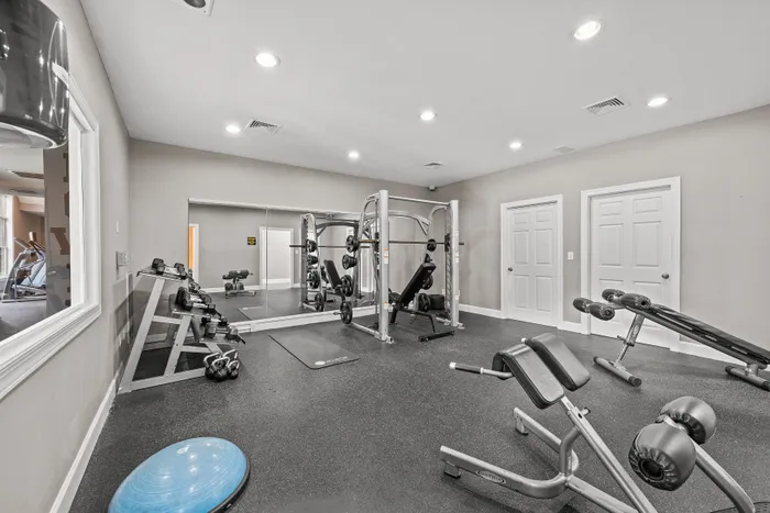Modern fitness center with state-of-the-art gym equipment, including weights, benches, and a functional trainer, set against sleek mirrored walls.