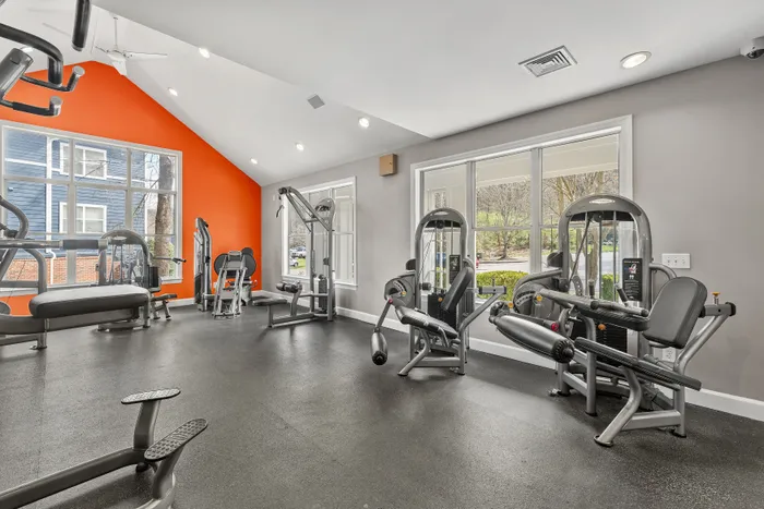 Bright and modern gym space with state-of-the-art exercise machines and vibrant orange accent wall.
