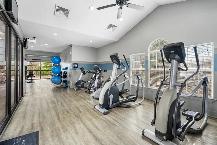 Modern fitness center with state-of-the-art cardio machines, ample natural light, and elegant wooden flooring.