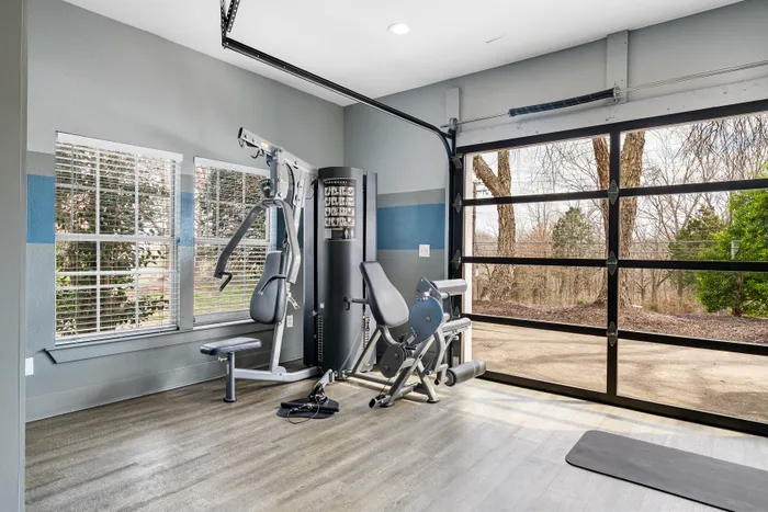 Bright home gym with state-of-the-art exercise equipment, featuring floor-to-ceiling windows and a serene outdoor view.