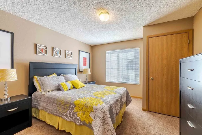 Bright and inviting bedroom featuring modern decor, a comfortable bed with stylish bedding, and ample natural light from a large window.