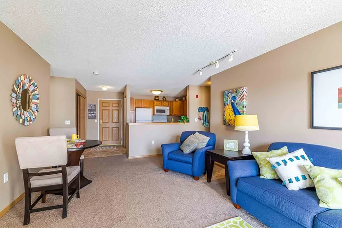 Inviting living room featuring a cozy blue sofa, stylish decor, and an open kitchen perfect for entertaining.