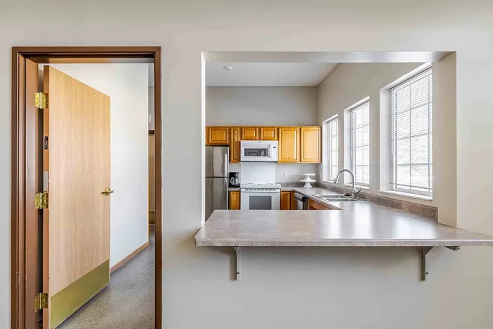 Bright and welcoming kitchen with sleek countertops, stainless steel appliances, and ample natural light from large windows.