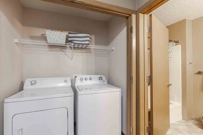 Bright and functional laundry area with modern washer and dryer, efficient use of space complemented by nearby bathroom access.