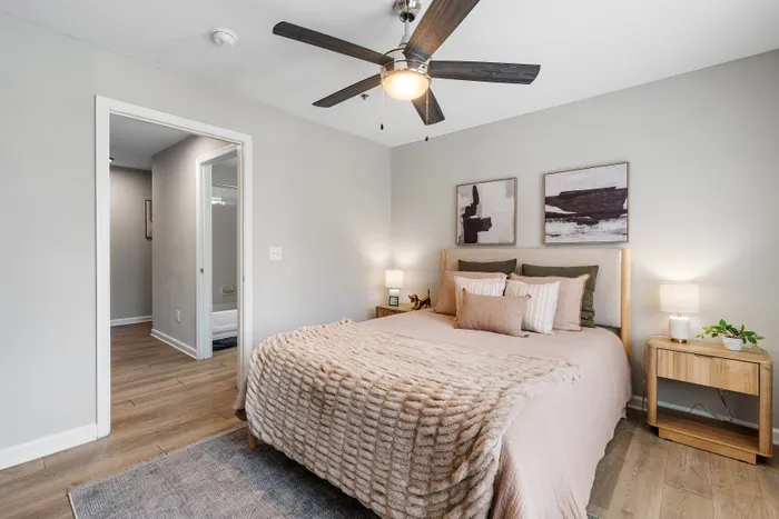 Inviting bedroom with a cozy, plush bed adorned with soft pillows and a fluffy beige blanket, complemented by modern artwork and warm lighting for a relaxing atmosphere.