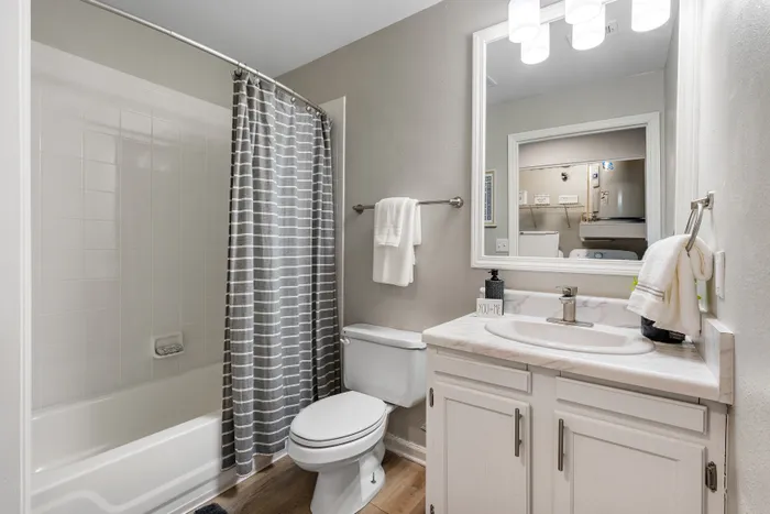 Elegant bathroom featuring a sleek shower bathtub combo, chic striped shower curtain, and a modern vanity with soft lighting.