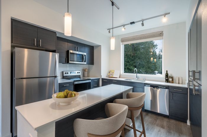 Modern kitchen with sleek stainless steel appliances, a stylish island with seating, and large window offering scenic views.