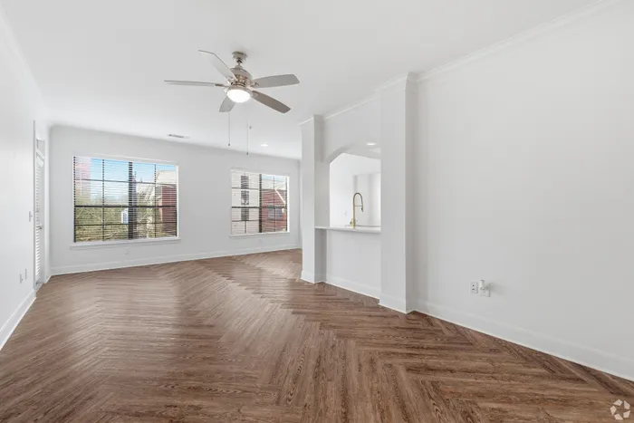 Bright and airy living room with elegant wood-patterned flooring, modern ceiling fan, and large windows providing natural light.