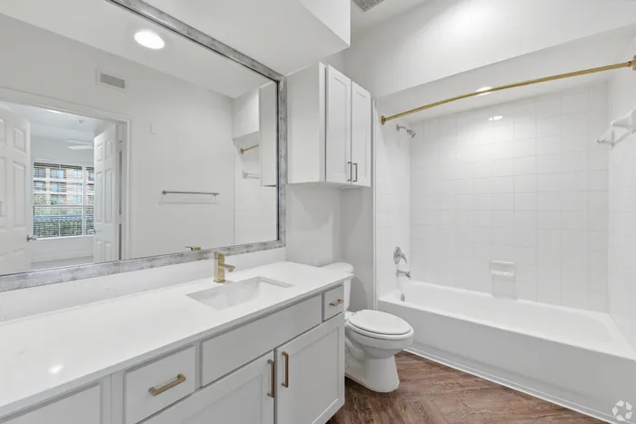 Bright and modern bathroom with sleek white cabinetry, polished countertops, and a spacious bathtub, offering a serene and inviting atmosphere.