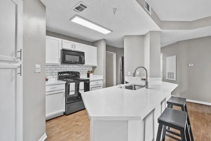 Modern kitchen with sleek white cabinetry, black appliances, and a spacious peninsula with seating, perfect for casual dining.