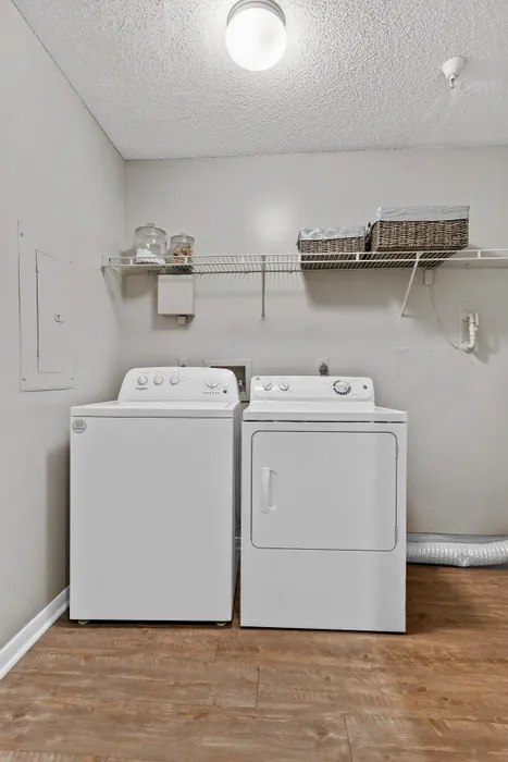 Inviting laundry room featuring modern washer and dryer on chic wooden flooring, with ample shelving for storage.