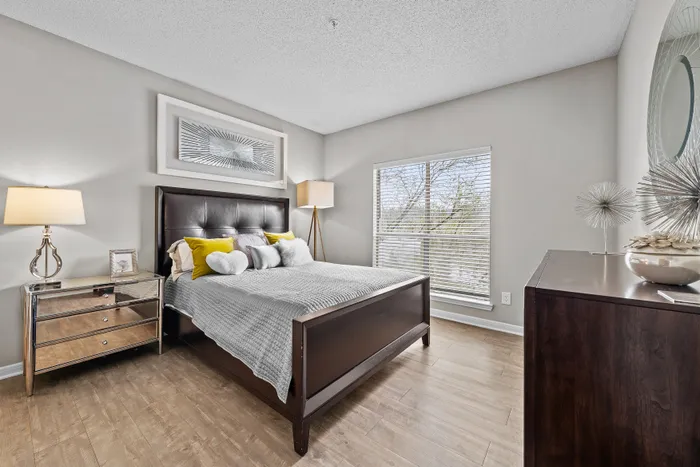 Bright and elegant bedroom with modern decor, featuring a comfortable bed with plush pillows, stylish lamps, and a large window offering scenic views.