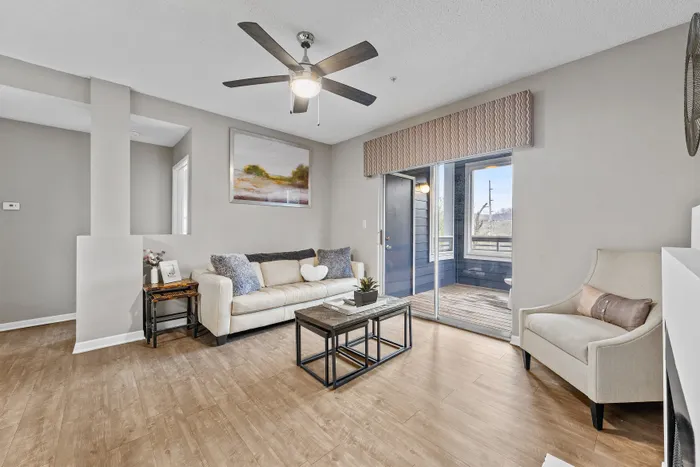 Inviting living room with elegant decor, featuring a plush sofa, modern coffee table, and large sliding doors opening to a cozy balcony.