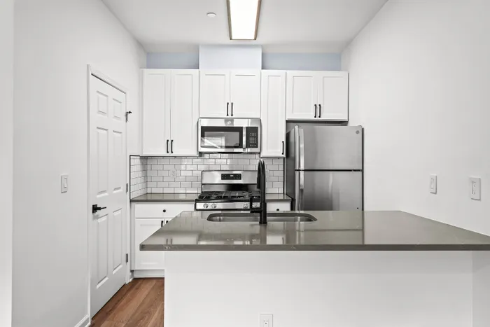 Modern kitchen featuring sleek stainless steel appliances, elegant white cabinetry, and a stylish subway tile backsplash.