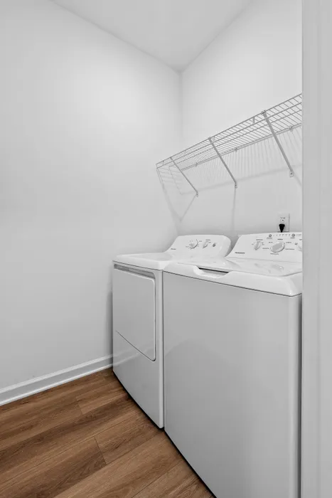 Sleek laundry area boasting modern washer and dryer with stylish shelving, featuring chic wood flooring.