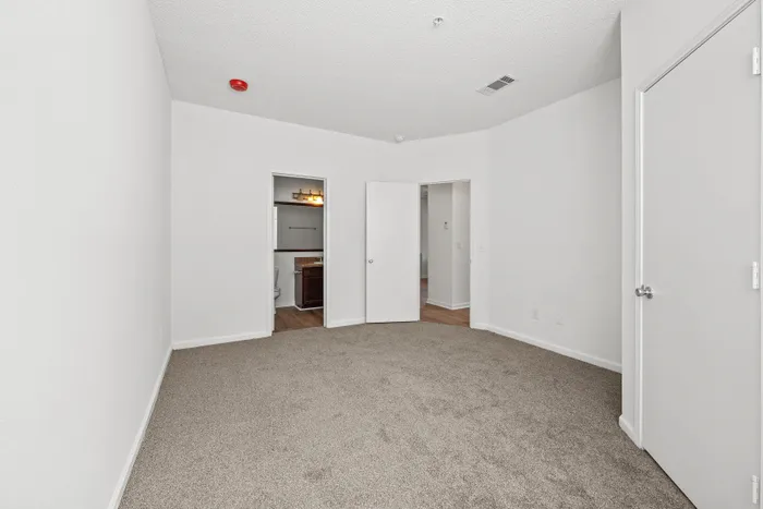 Spacious and inviting bedroom with plush carpet, adjacent bathroom, and modern finishes.