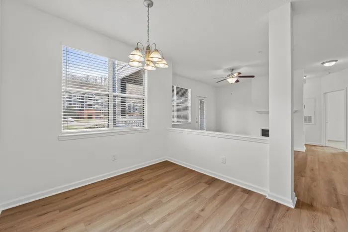 Bright, open living space with elegant wood flooring, modern light fixtures, and expansive windows offering excellent natural light.