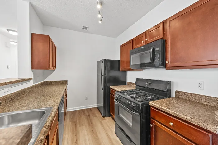Stylish kitchen with rich wooden cabinetry, sleek countertops, and modern appliances including a black stove and microwave.