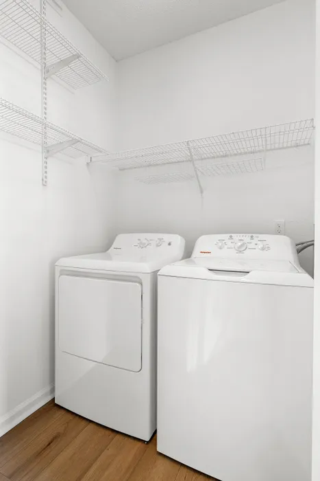 Bright, modern laundry room with energy-efficient washer and dryer, featuring ample shelving for storage.
