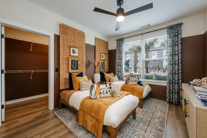 Inviting twin bedroom with chic decor, warm tones, and a spacious walk-in closet, perfect for a stylish and cozy retreat.