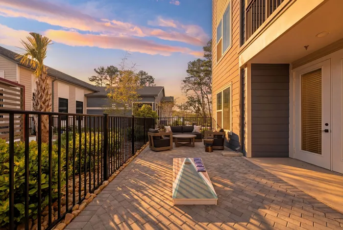 Charming patio at sunset with cozy outdoor seating and a fun cornhole game area, perfect for relaxation and entertainment.