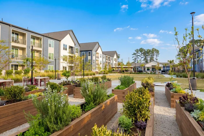 Charming apartment complex with modern design, surrounded by lush gardens and cozy outdoor seating.